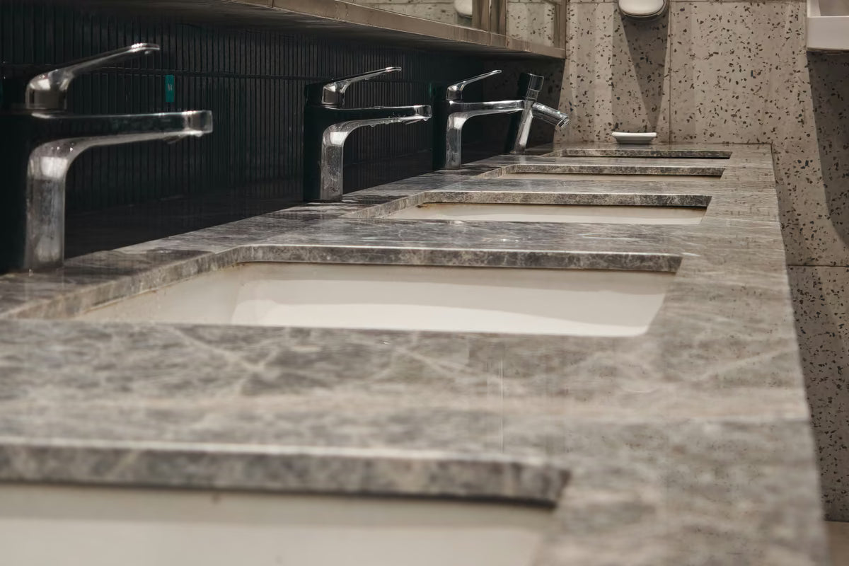 Fila de torneiras em bancada de lavatórios de banheiro público