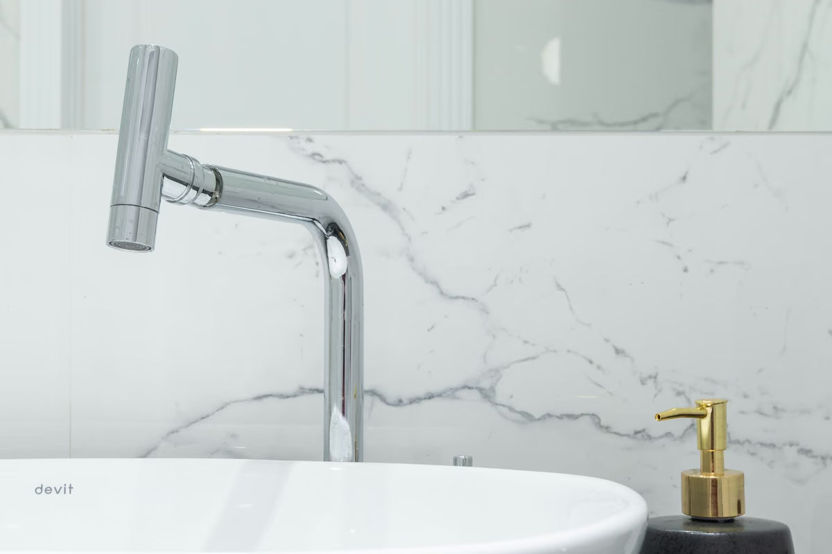 Torneira de inox alta em lavatório branco com parede de mármore