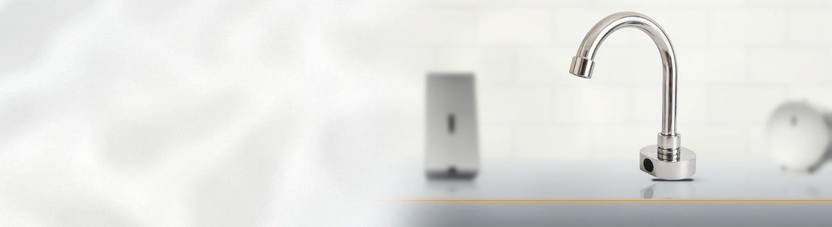 Torneira com sensor de aço inox instalada em bancada, com dispensers desfocados ao fundo