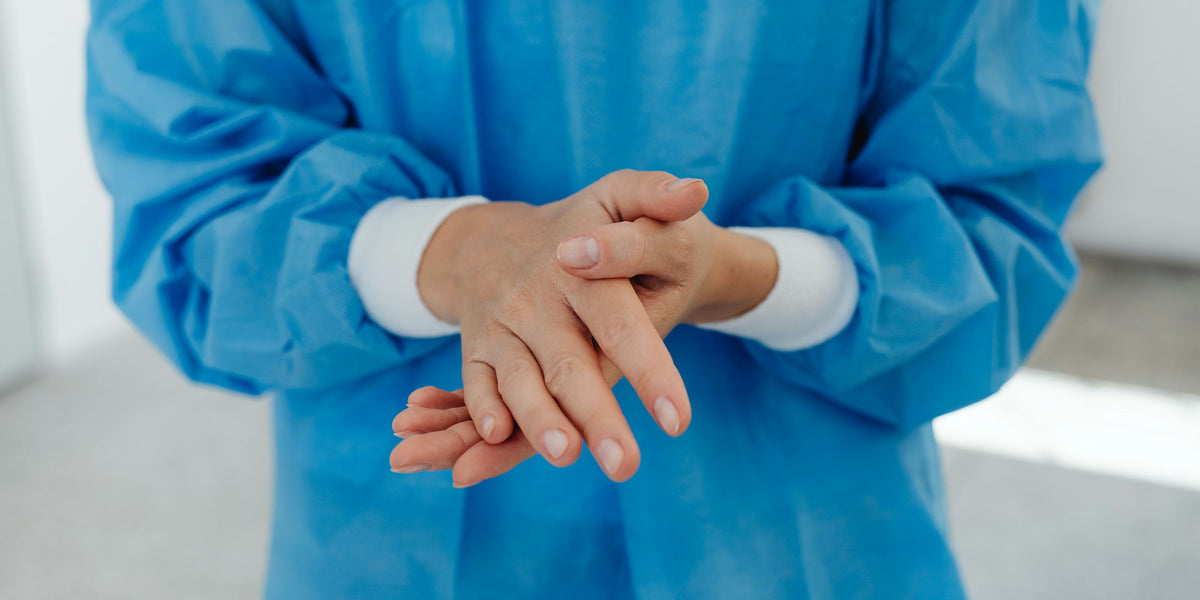 Profissional de avental azul higienizando as mãos
