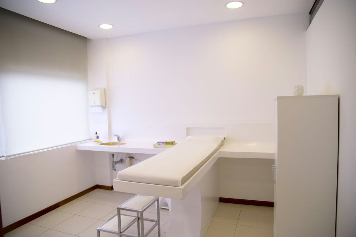 Sala de exame clínica com maca e bancada branca