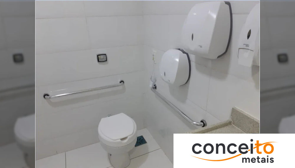 Banheiro adaptado com barra de apoio horizontal em inox ao lado do vaso sanitário e dispensadores de papel toalha e h...