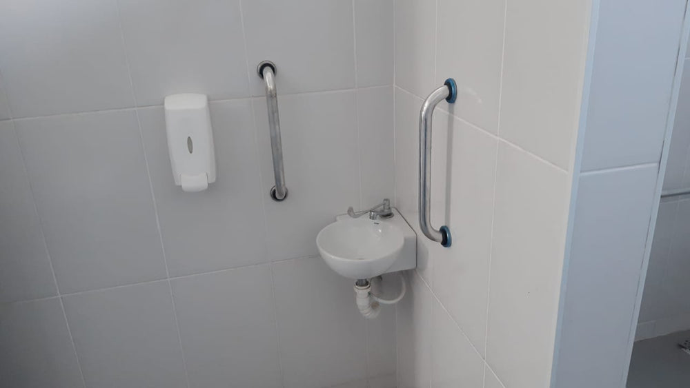 Lavatório compacto com barras de apoio verticais instaladas em ambos os lados, dispensador de sabonete e torneira cro...