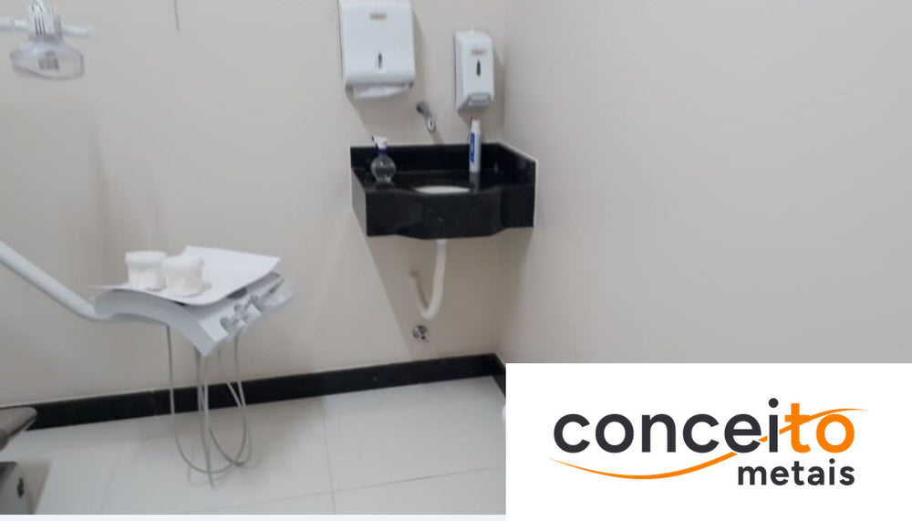 Consultório odontológico equipado com pia clínica de canto, dispensador de papel toalha e saboneteira, além da bandej...